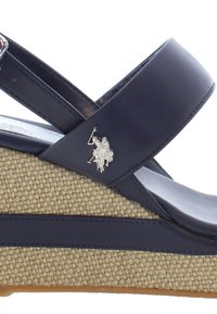 Navy blue wedgesandaalit, joissa on teksturoitu beige kudottu pohja, varustettuna hopeisella logokaiverruksella hihnassa ja kiiltävällä yläosalla.