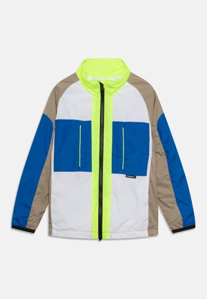 Bunt gefütterte Windjacke in Blau, Weiß, Beige und Neon Grün mit einem Front-Reißverschluss und zwei Brusttaschen.