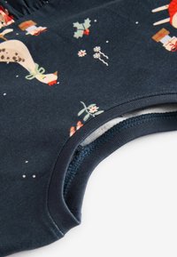 Chemise en coton doux bleu marine avec des motifs festifs d'animaux, de cadeaux et de feuillage, dotée d'un col rond et d'un ourlet surpiqué.