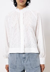 Weißes Blusentop mit kunstvoller Paisley-Stickerei, gerafftem Ausschnitt und Knopfleiste. Strukturierter Stoff mit lässigem Schnitt und langen Ärmeln.
