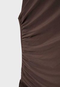 Nahaufnahme eines braunen Stoffs mit gesammelter, geraffter Naht entlang einer Seite.