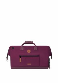 Sac de voyage en tissu violet avec une poche zippée à l'avant, des accents en cuir, des poignées supérieures doubles et un logo circulaire. Texture lisse, forme rectangulaire.
