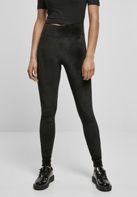 Sorte tights, høyt liv, laget av mykt, glatt materiale med en lett glans. Brukt med blanke svarte sko. Tettsittende design.