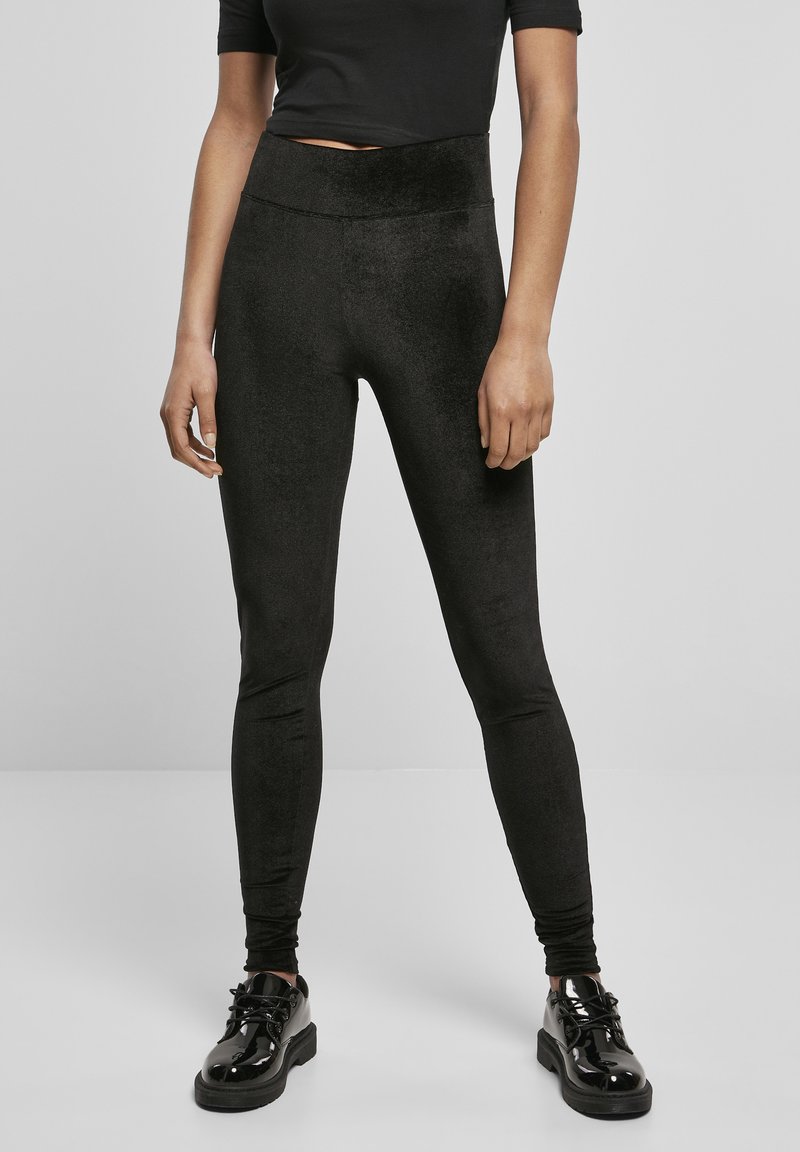 Sorte tights, høyt liv, laget av mykt, glatt materiale med en lett glans. Brukt med blanke svarte sko. Tettsittende design.
