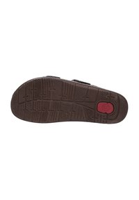 Brown rubber shoe sole featuring textured patterns for grip, a red accent button, and patterned grooves for traction.