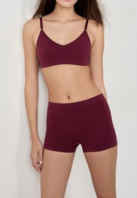 Bralette bordeaux et shorts assortis en tissu doux. Le bralette présente des bretelles fines, tandis que les shorts ont une taille élastique confortable.