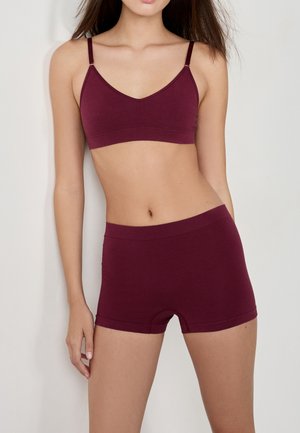 Bralette bordeaux e pantaloni coordinati realizzati in tessuto morbido. Il bralette presenta spalline sottili, mentre i pantaloni hanno una comoda vita elastica.