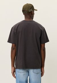 Μαύρο γκρι T-shirt με χαλαρή εφαρμογή, κοντά μανίκια και στρογγυλή λαιμόκοψη, σε συνδυασμό με τζιν ανοιχτού μπλε χρώματος. Καθημερινό, απαλό βαμβακερό υλικό.