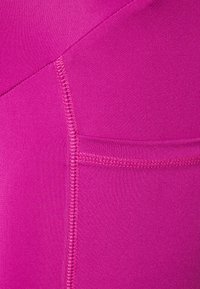 Calções atléticos ajustados em tecido rosa vibrante com uma textura suave, apresentando costuras planas e um pequeno bolso lateral.