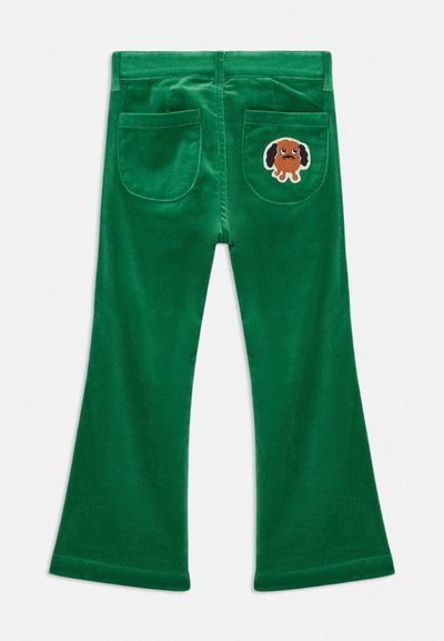 Πράσινο παντελόνι βελούδινο με δύο πίσω τσέπες, μία από τις οποίες έχει ένα μικρό μπαλώμα με καφέ σκύλο με μαύρα αυτιά και λευκό περίγραμμα.