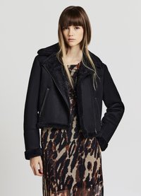 Giacca nera corta con colletto e polsini in pelliccia, dotata di tasche frontali con zip e una superficie esterna liscia.