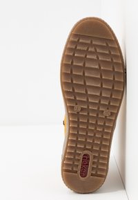 Semelle d'une chaussure en caoutchouc marron avec un motif de crampons en grille, taille 37 indiquée, et logo rouge "rieker" incrusté près du talon.