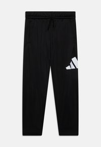Pantalons de sport noirs avec une taille élastique, un cordon de serrage, des poches latérales et un grand logo Adidas blanc sur la cuisse gauche.
