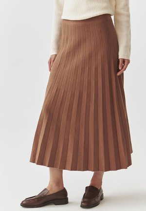 Jupe midi plissée marron en matériau texturé avec une taille ajustée. Associée à des chaussures à enfiler marron foncé.