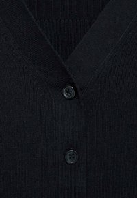 Zwarte cardigan met een V-hals ontwerp, geribbelde textuur en drie zwarte knopen aan de voorkant. De stof lijkt zacht en warm.