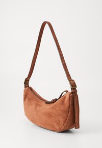 Borsa a spalla in suede arancione bruciato, design curvo, chiusura con zip, tracolla in pelle regolabile con fibbia metallica e dettaglio a nodo.