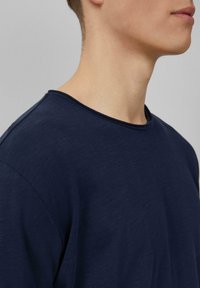 Marineblauwe katoenen T-shirt met een ronde halslijn, korte mouwen en een zachte, gladde textuur. Beschikt over een relaxte pasvorm en een eenvoudig ontwerp.