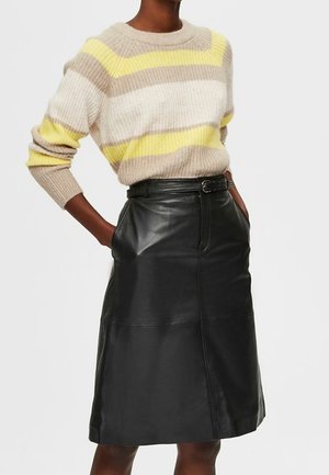 Gebreide trui met beige, crème en gele strepen; gecombineerd met een hoge zwarte leren rok, voorzien van zijzakken en een riem.