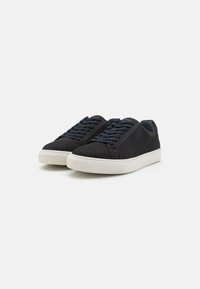 Black suede sneakers with round toe, navy laces, and contrasting white rubber sole. Smooth texture and minimalist design.