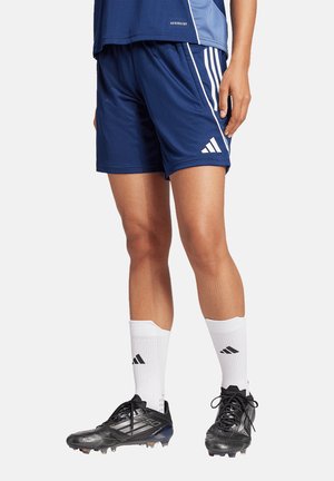 Marine sportieve shorts met witte strepen, gemaakt van ademend materiaal. Gecombineerd met zwarte voetbalschoenen en witte sokken met een logo.