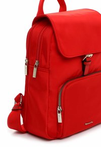 Mochila de tela roja con múltiples compartimentos con cremallera, correas ajustables y detalles metálicos en las cremalleras. Textura suave y diseño estructurado.