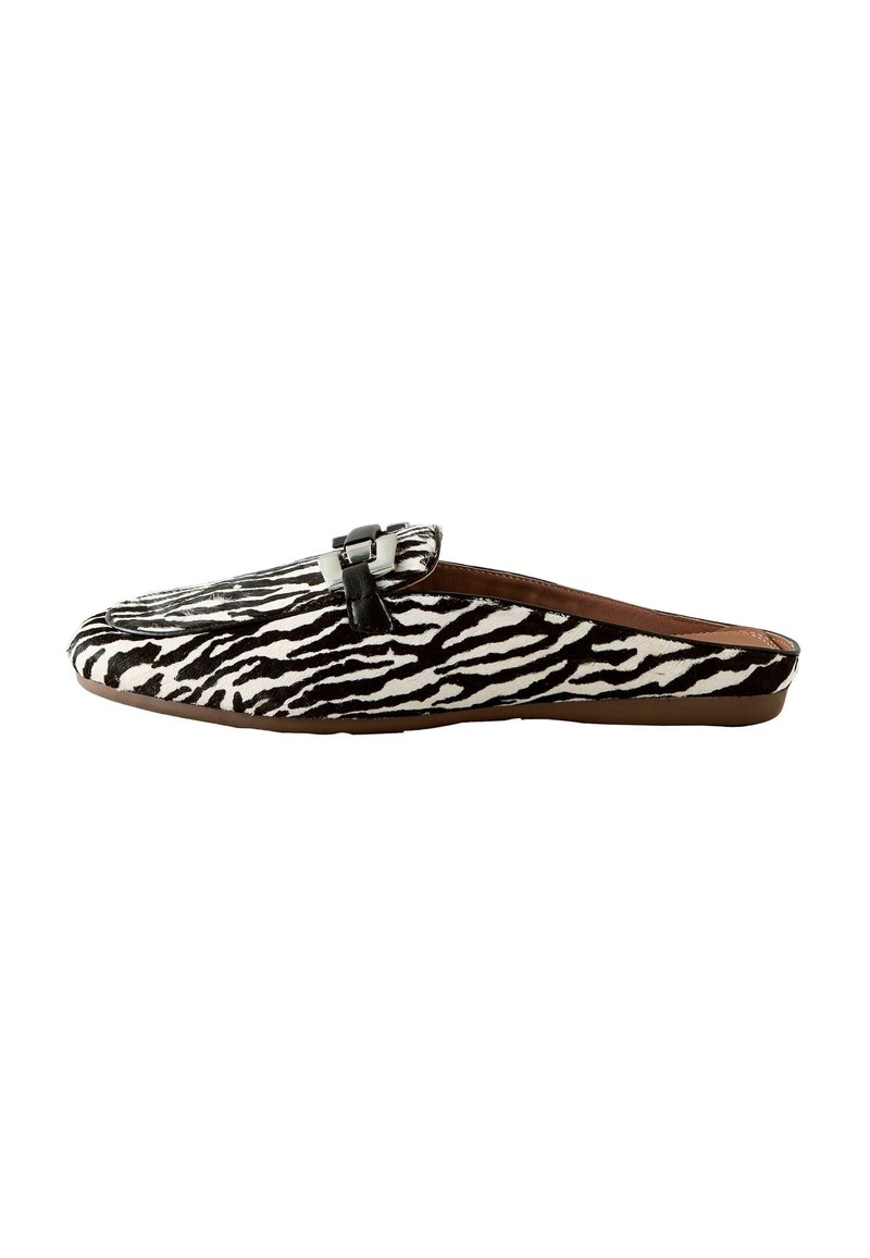 Mule à enfiler avec motif zèbre noir et blanc et détail boucle noire sur le dessus, semelle plate marron.