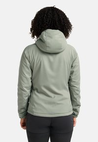 Giacca isolante verde chiaro con cappuccio, caratterizzata da una texture liscia e un design aderente, cuciture visibili e polsini elasticizzati.