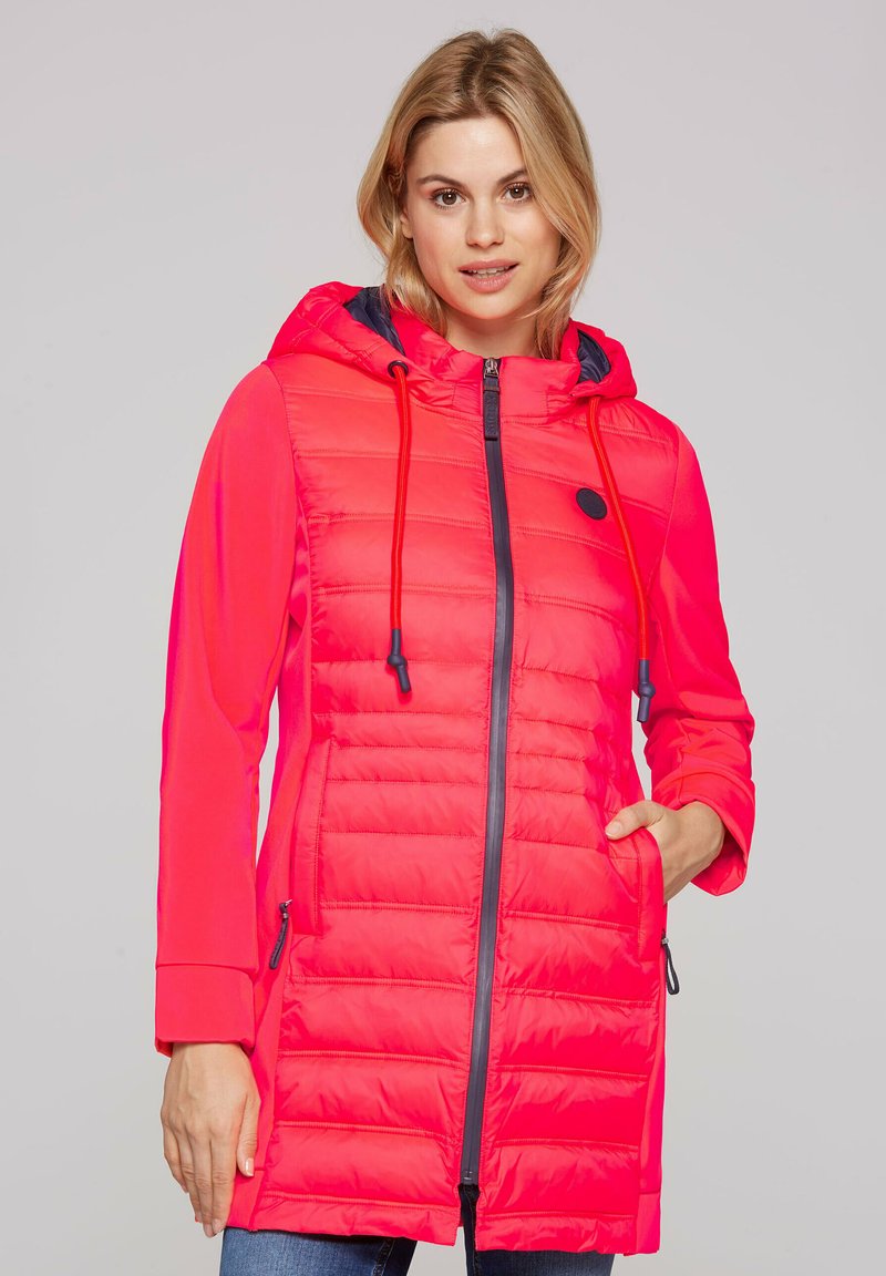 Padded pink jacket with a hood, featuring navy accents, zip closure, and drawstring. Light texture with pockets on both sides.