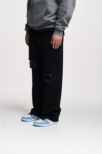 Black distressed jeans with ripped knees, paired with white and light blue sneakers. Grey hoodie features a front pocket.