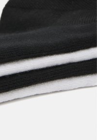 Chaussettes rayées noir et blanc en tissu doux, avec une texture côtelée et des coutures plates pour le confort et l'ajustement.