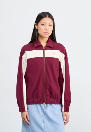 Burgundy and cream zip-up jacket with a collar, ribbed cuffs, and hem. Features a gold logo on the chest and textured fabric.