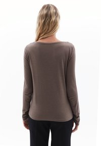 Een bruine, langärmelige shirt met een zachte textuur en een ronde halslijn, bekeken vanuit de achterkant. Geen zichtbare logo's of patronen.