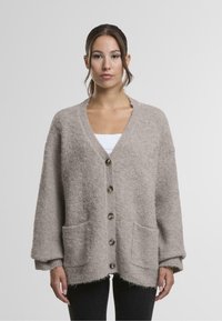 Svetlo rjav, strukturiran cardigan z V-izrezom, tremi gumbi in sprednjimi žepi. Ima široke rokave in nekoliko skrajšan rob.