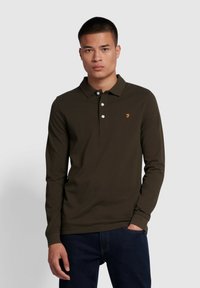 Bruine langambige polo met kraag, drie witte knopen en een klein oranje logo. Glad textura en aansluitend ontwerp.