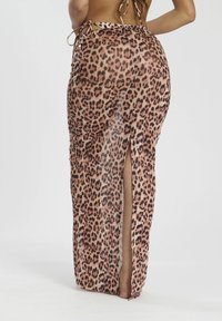 Falda maxi con estampado de leopardo y una abertura alta, hecha de tela ligera, con detalles de lazo en la cintura y una textura suave.