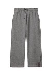 Graue weite Jogginghosen mit elastischem Bund, Kordelzug, seitlichen Taschen, kleinen Seitenschlitzen und einem "DREAM"-Etikett in der Nähe des Saums.