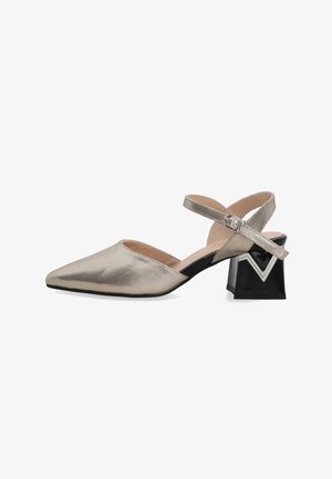 Metallic gold pointed-toe shoe with an ankle strap and unique black block heel featuring a decorative silver accent. Smooth texture.