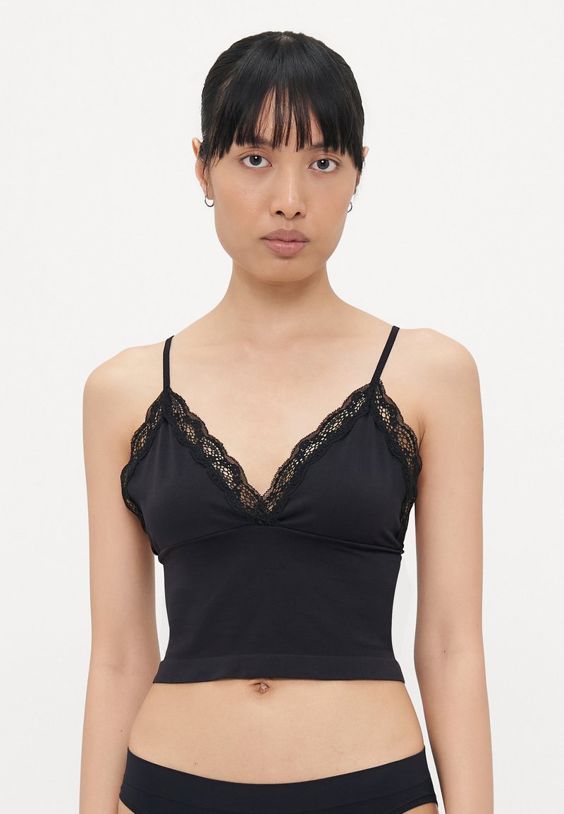 Crni bralet s V-izrezom koji ima složen čipkasti rub, izrađen od mekog materijala s uskim krojem. Podešive naramenice.