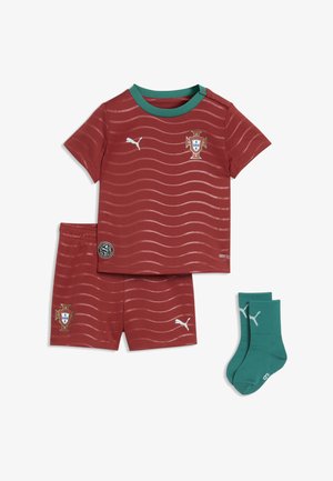 Rood sportset met golvende strepen, bestaande uit een shirt met een groene kraag, short en turquoise sokken. Voorzien van logo-accenten en emblemen.