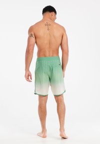 Groene gradient zwemshorts met een textuurpatroon, elastische tailleband en contrasterende groene rand. Achterzak aan de rechterkant.