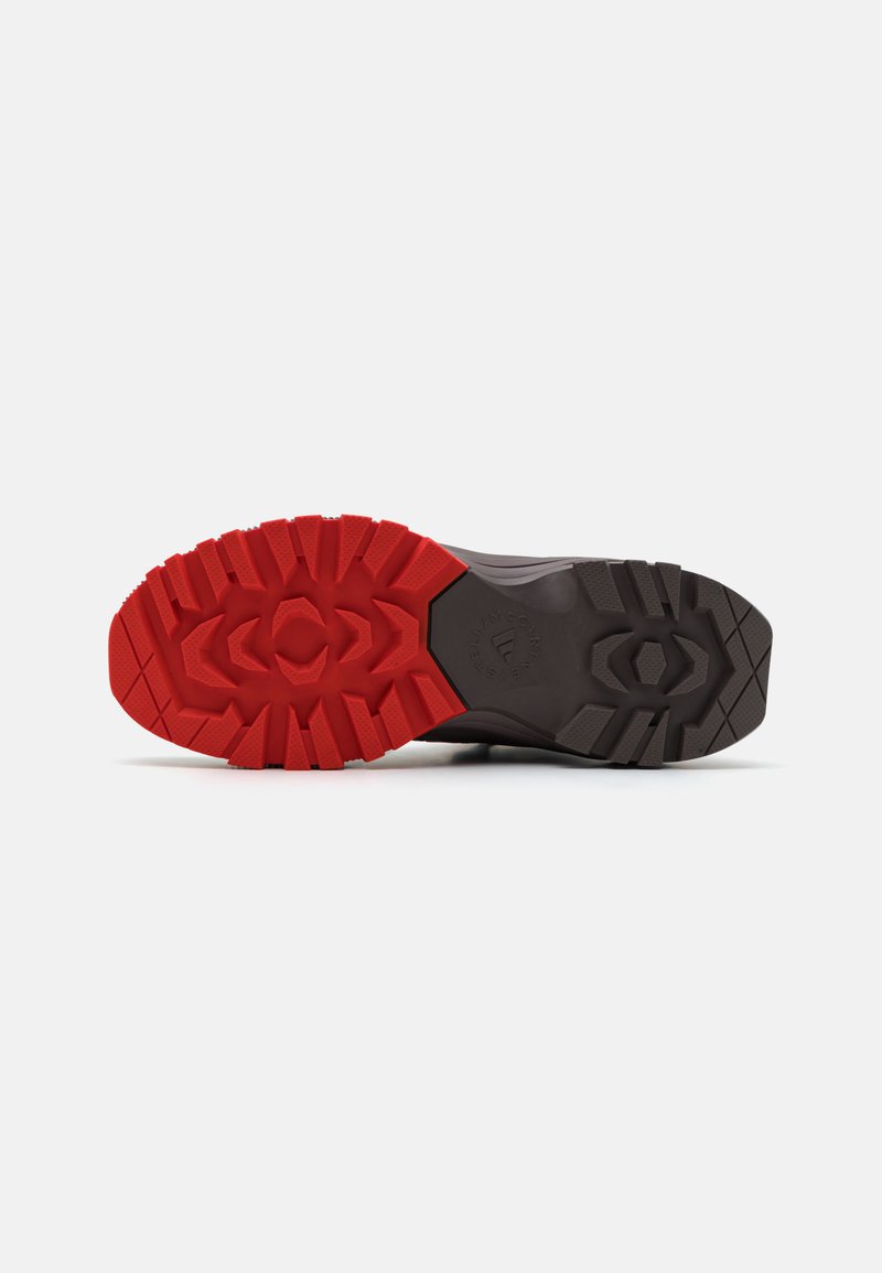 Sko sål med et tykt mønster, der har rød tekstureret gummi foran og sort ved hælen, designet til greb og holdbarhed.