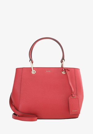 Sac à main en cuir rouge DKNY avec double poignée supérieure, bandoulière amovible et étiquette de bagage assortie à la marque.