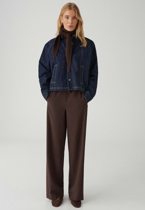 Spijkerjack met een cropped ontwerp, donkerblauwe kleur, voorzakken en een bruine gebreide sjaal; gecombineerd met brede bruine pantalon.