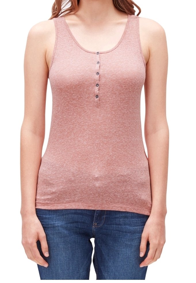 Mujer vestida con una camiseta sin mangas henley rosa con cinco botones y jeans de mezclilla azul, de pie con los brazos relajados a los lados.