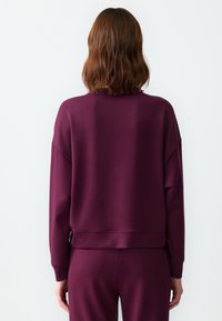 Felpa color berry con vestibilità rilassata, polsini e orlo a costine. Tessuto morbido e liscio, progettata per il comfort e l'abbigliamento casual.