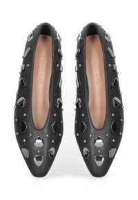 Zwarte platte schoenen met een spitse neus, voorzien van zilveren en zwarte studs in verschillende vormen, en een zachte leren bovenkant. Gevoerde binnenkant.