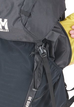 Black and gray Millet Davis 30 backpack with mesh side pocket and a hand adjusting the top zipper.