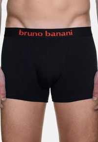 Boxer neri realizzati in tessuto morbido con una fascia rossa con logo. Presentano un design attillato e una tasca sagomata.