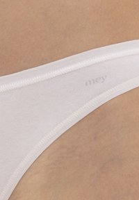 Witte katoenen thong met zachte elastische tailleband en minimalistisch ontwerp. Heeft subtiele branding en een gladde textuur, geschikt voor dagelijks gebruik.