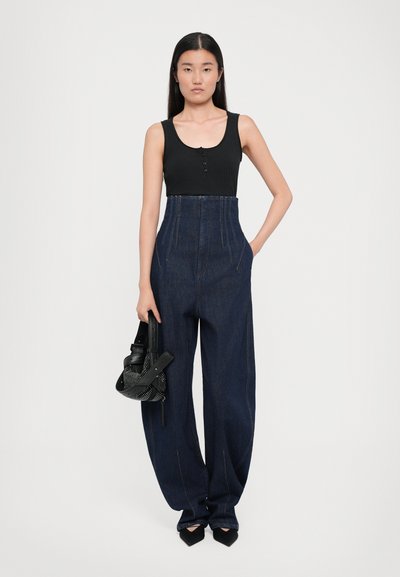 Top din bumbac negru cu nervuri, cu detalii cu butoane, asortat cu pantaloni din denim închis, cu talie înaltă, având picioare largi și cusături vizibile.